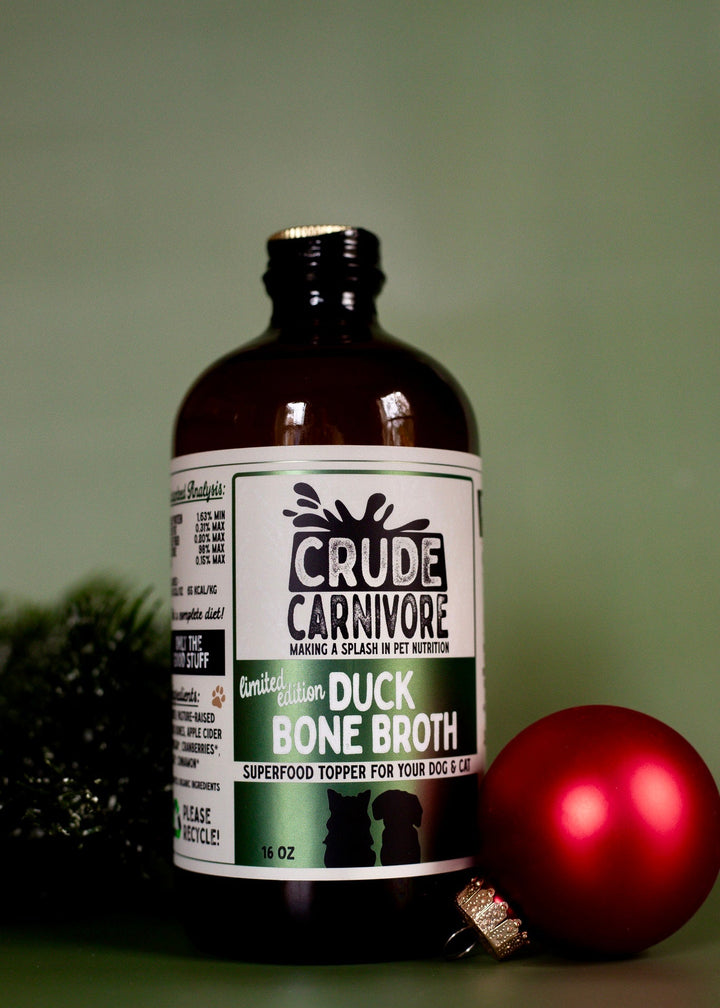 Bottle of Crude Carnivore duck bone broth with a red ornament on a green background