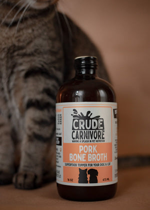 Bottle of Crude Carnivore Pork Bone Broth with a cat in the background