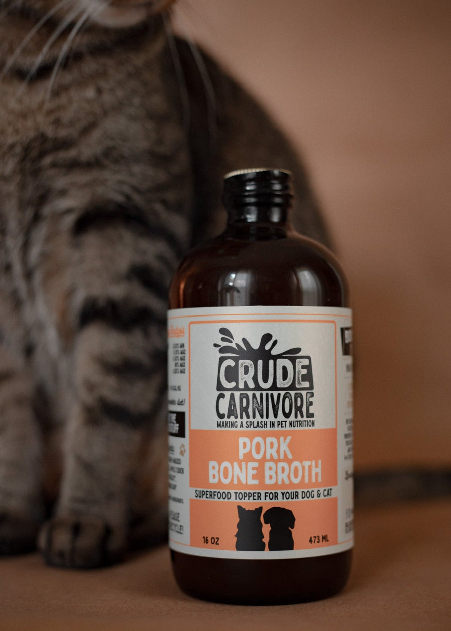 Bottle of Crude Carnivore Pork Bone Broth with a cat in the background
